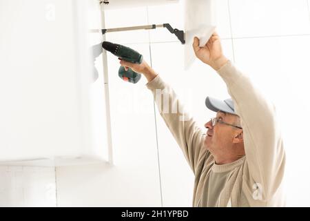 Mature Male Serviceman Repairing With Toolbox In Kitchen Stock Photo