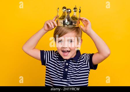 Photo portrait little boy wearing striped clothes crown smiling overjoyed isolated vibrant yellow color background Stock Photo