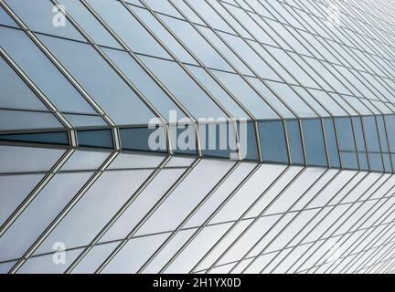 Semi-transparent glass windows of a skyscraper wall, with a change of symmetry in the center windows, with vanishing point; viewed from below. Backgro Stock Photo