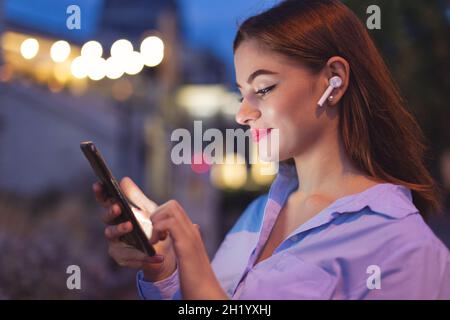 Young businesswoman writing message on phone at evening outdoors in city Stock Photo