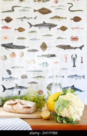 Bread, cauliflower, dill, melon, lemon and a water carafe in front of fish wallpaper Stock Photo