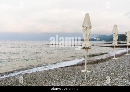 Cloudy weather and empty pebble beach with closed sun loungers Stock Photo