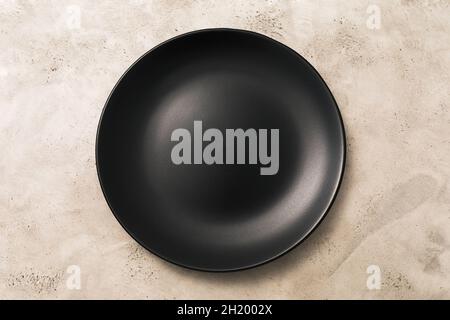Empty black ceramic plate on light abstract background, top view, food background Stock Photo