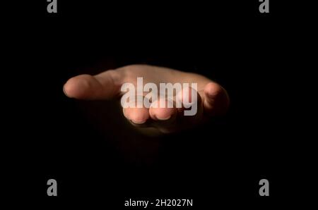 Hand gesture on a black background, palm up holding something, mockup and template for presentation concept Stock Photo