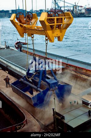 Feed cereals being  loaded ship to ship by means of a grabbing crane in the Port of Hamburg. Stock Photo
