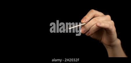 Banner business person with hand holding silver pen to point isolated on a black background. Concept of successful job, touch symbol, digital writing Stock Photo