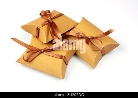 Small gifts in a box made of natural cardboard. The craft box is tied with a brown satin ribbon. Group of gifts, copy space. Gift boxes with recycled Stock Photo