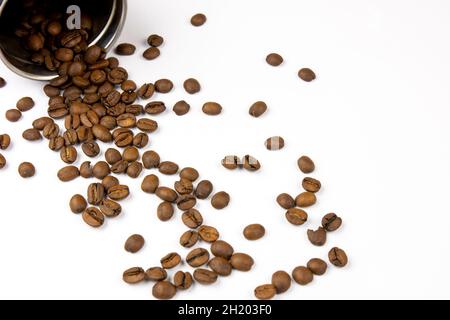 Roasted coffee beans on a white background. Overturned coffee can, coffee beans scattered on the table Stock Photo