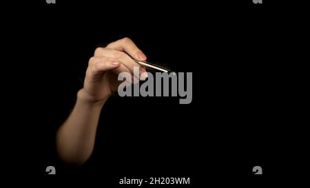 Hand holding silver pen isolated on a black background. Signature concept, blank empty copy space Stock Photo