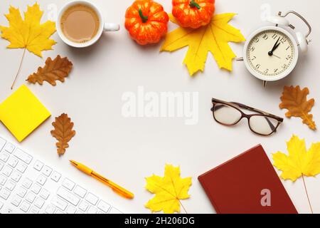 Autumn desktop concept. Alarm clock coffee cup keyboard with autumn leaves and pumpkins. Top view flat lay copy space Stock Photo