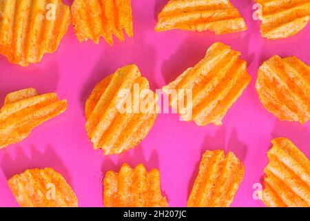 Ribbed potatoes snack with pepper on pink background. Ridged potato chips on pink background. Set of potato chips. Flat lay. Close-up Stock Photo