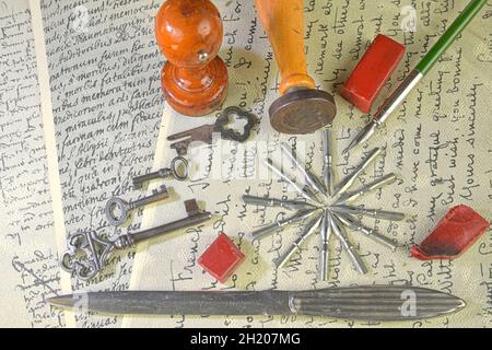 Close-up of accessories on vintage handwriting. Vintage keys, wooden stampers, sealing wax, paper knife, metal nibs and old pen. Vintage stationery Stock Photo