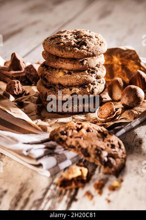 Chocolate chip cookies and hazelnuts on a piece of brown paper and a tea towel Stock Photo