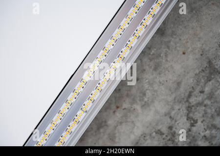 Strip LED light with aluminum profile. Stretch ceiling with LED lighting in house or apartment, indoor, close up. Home renovation concept. Energy savi Stock Photo