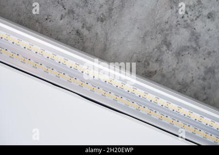 Strip LED light with aluminum profile. Stretch ceiling with LED lighting in house or apartment, indoor, close up. Home renovation concept. Energy savi Stock Photo