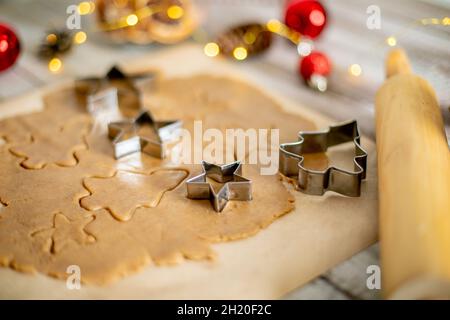 Raw dough for cookies, cookie cutters and festive decoration on wooden table. Concept of Christmas sweet food Stock Photo