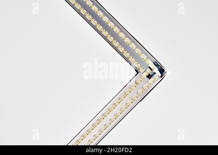 Strip LED lamp lighting with square aluminum profile on suspended ceiling in house, fragment, close up. Home renovation concept and remodeling. Energy Stock Photo