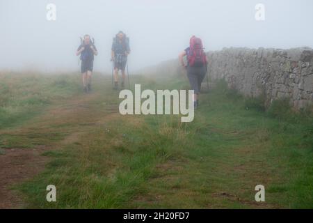 Hikers in mist on Hadrians Wall in Northumberland National Park England. The Hadrian’s Wall Path is an 84 mile Stock Photo