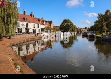 Boats moored on the Great Ouse River with Cutter Inn and riverside properties in Ely Cambridgeshire England Stock Photo