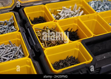 Yellow case with small construction objects. Many storage compartments filled with builders accessories containing screws, nuts, bolts, nails and othe Stock Photo