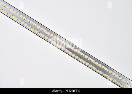Strip LED light with aluminum profile on white stretch ceiling in house or apartment, indoor close up. Home renovation concept. Modern construction, e Stock Photo