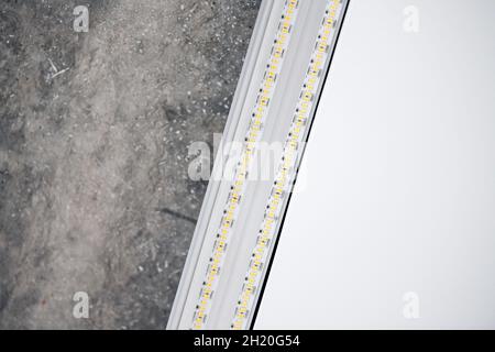 Strip LED light with aluminum profile. Stretch ceiling with LED lighting in house or apartment, indoor, close up. Home renovation concept. Energy savi Stock Photo