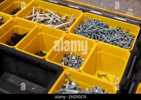 Yellow case with small construction objects. Many storage compartments filled with builders accessories containing screws, nuts, bolts, nails and othe Stock Photo