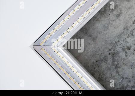 Strip LED light with square aluminum profile. Stretch ceiling with LED lighting in residential building, indoor photo, close up. Home renovation conce Stock Photo