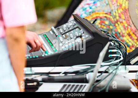 Sound engineer hand adjusting audio mixer at live concert outdoor, sliders and buttons on audio mixing console desk. Professional stage sound mixer at Stock Photo