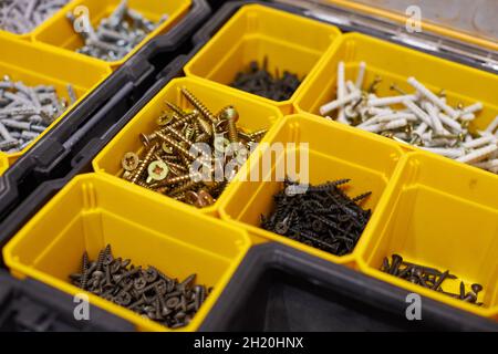 Yellow case with small construction objects. Many storage compartments filled with builders accessories containing screws, nuts, bolts, nails and othe Stock Photo