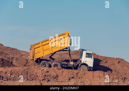 White dump truck dumping sand and soil material at an outdoor ...
