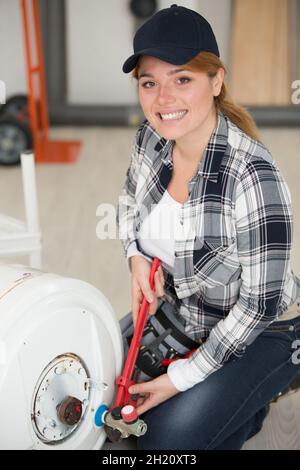 happy female plumber working on central heating boiler Stock Photo