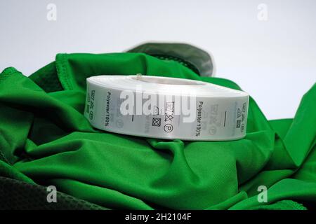 Skein tags for clothing, satin ribbon with symbols for the use of clothing. Green 100 % Polyester fabric Clothing label with laundry instructions. Lab Stock Photo