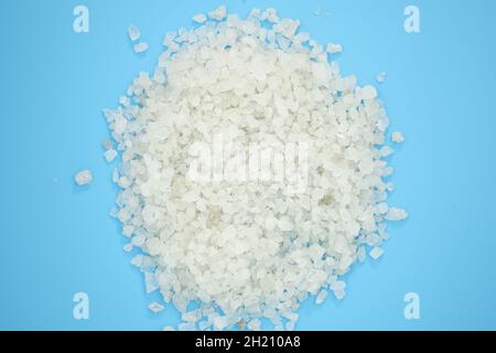 White sea salt grain top view. Coarse salt on a blue background. Pile of natural salt on color background Stock Photo