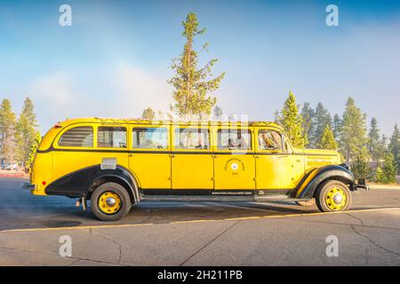 Vintage Yellowstone National Park shuttle bus is parked at the Old Faithful Inn, Wyoming, USA Stock Photo