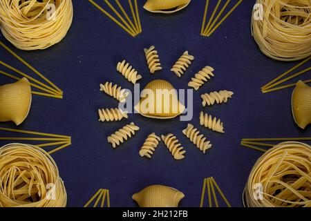 Advertising of different pasta diagonally Mixed pasta, spaghetti, horns, spirals and shells on a blue background for advertising menu. Stock Photo