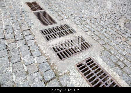 cobbleston granite stone road with drainage grates for storm water drainage urban streets improvement in the old city close-up, nobody. Stock Photo