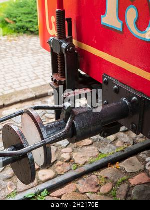 Coupling connects hooks on the adjoining red wagons. Type of connection between tram cars with buffer and hook coupling. Two cars of retro tram couple Stock Photo