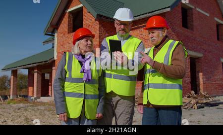 Real estate agent manager architect showing modern house to senior grandparents family client couple Stock Photo