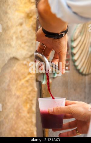 Pilgrims using the wine fountain at the Bodegas Irache at Ayegui  Navarra while walking the Camino de Santiago the way of St James pilgrimage route Stock Photo