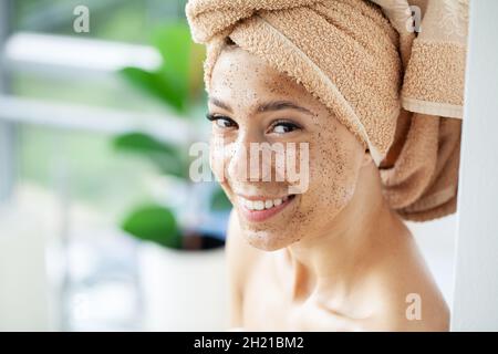 Young beautiful girl applying facial scrub mask on skin. Stock Photo
