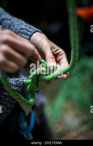 Detail with a climber's hands tying a figure eight know to the harness. Stock Photo