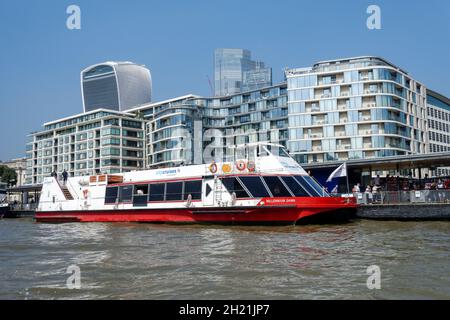 Tourists cruise boat at the Tower Pier with the City of London skyscrapers in the background, London England United Kingdom UK Stock Photo