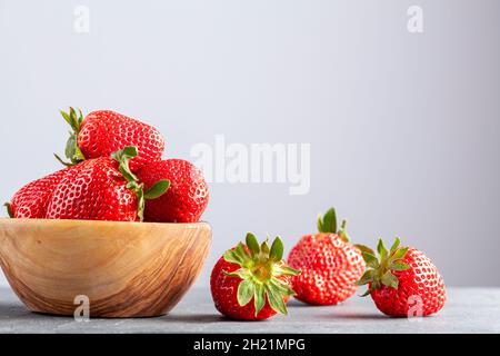 Close up isolated image of a wooden wooden bowl filled with fresh raw strawberries on dark stone background. Full of nutrient, raw organic food for he Stock Photo