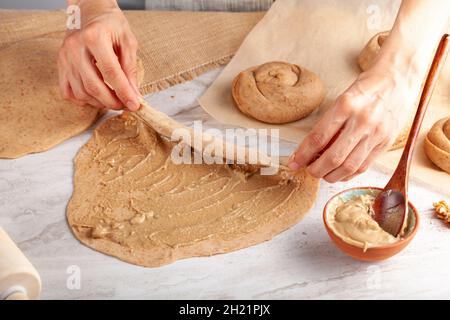closeup isolated image of a caucasian woman preparing sweet Turkish pastry rolls with tahini and petimezi. She wraps the rolls with spread filled insi Stock Photo