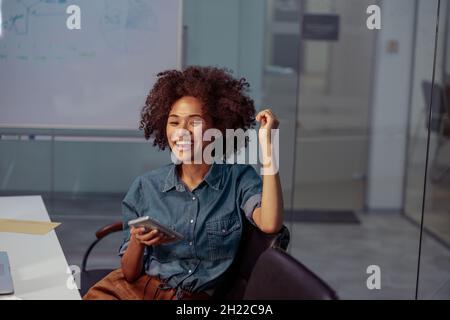 Smiling pretty lady sitting on chair in the meeting room Stock Photo