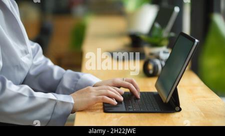 Side view, business woman working on portable tablet computer, typing her works on tablet. Stock Photo