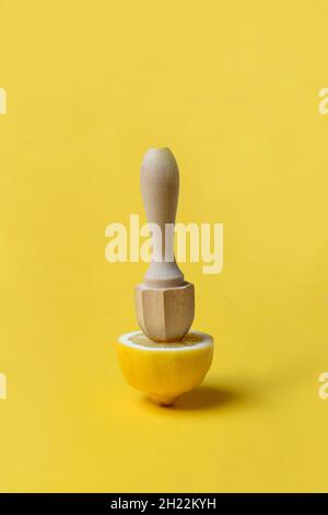 Lemon and lemon squeezer against a yellow background Stock Photo