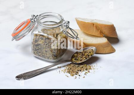 Dukkah, Arabic spice mixture in glass container and spoon, slices of bread Stock Photo