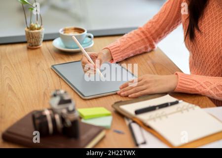 Cropped close-up image of attractive millennial female graphic designer designing and sketching her graphic works on tablet computer. Stock Photo